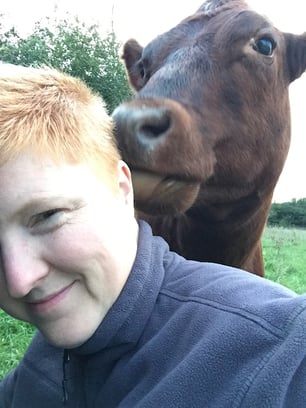 Sarah Bakker Field Sparrow Farms with a cow in the back lick her ear