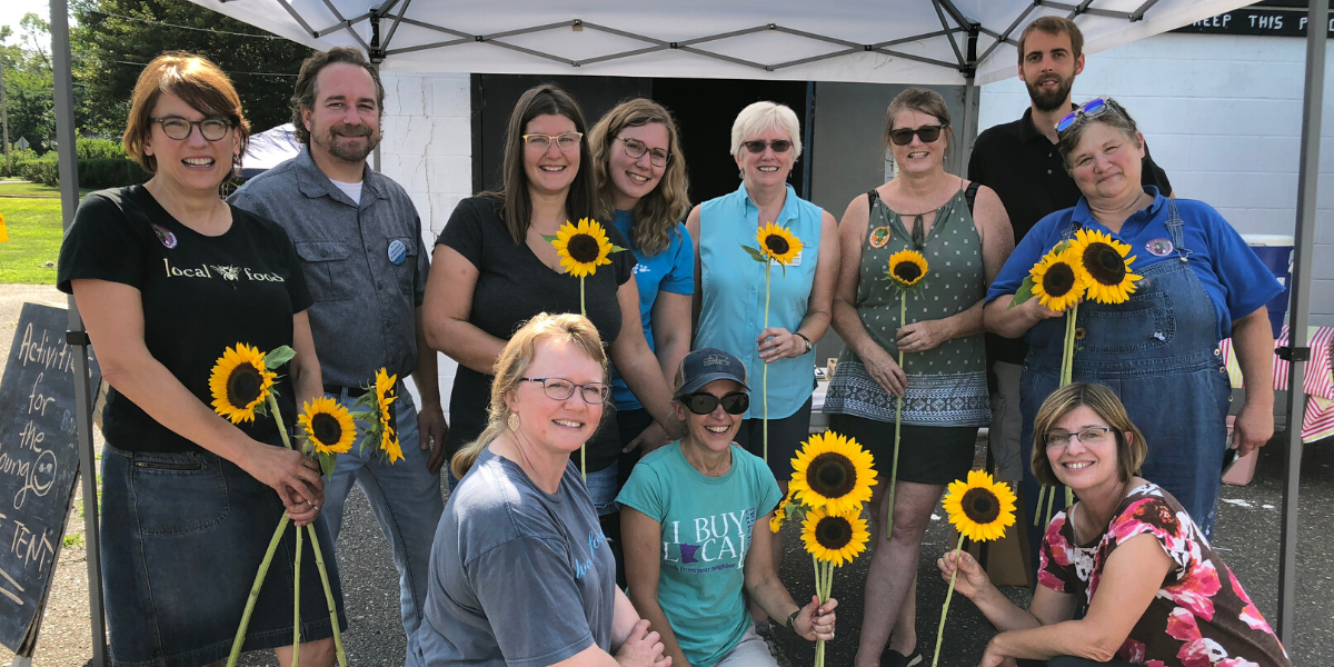 Minnesota Farmers' Market Association members smiling and holding sunflowers